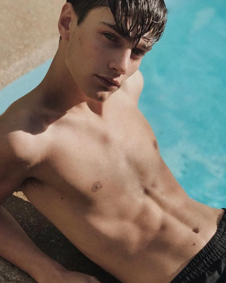 Homme torse nu, regardant l’appareil, main dans les cheveux, ceinture noire, jeans