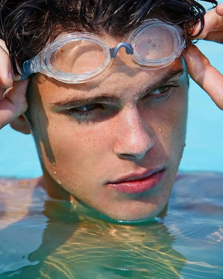 Homme dans une piscine, lunettes de natation sur le front, regardant l’appareil