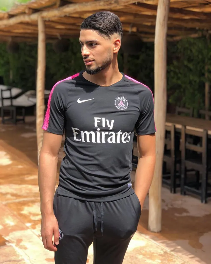 Homme arabe de 25 à 35 ans, torse nu, portant un t-shirt blanc, sous-vêtement Calvin Klein, devant un rideau jaune.
