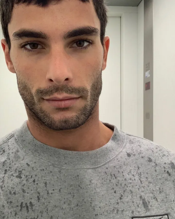 Homme torse nu, debout, regardant directement l'appareil photo, avec une main sur la hanche.